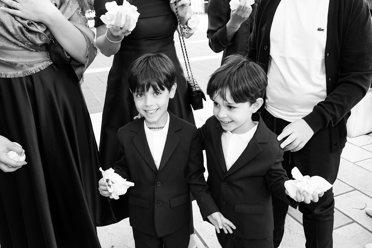 Two young boys in matching black suits at a formal event.