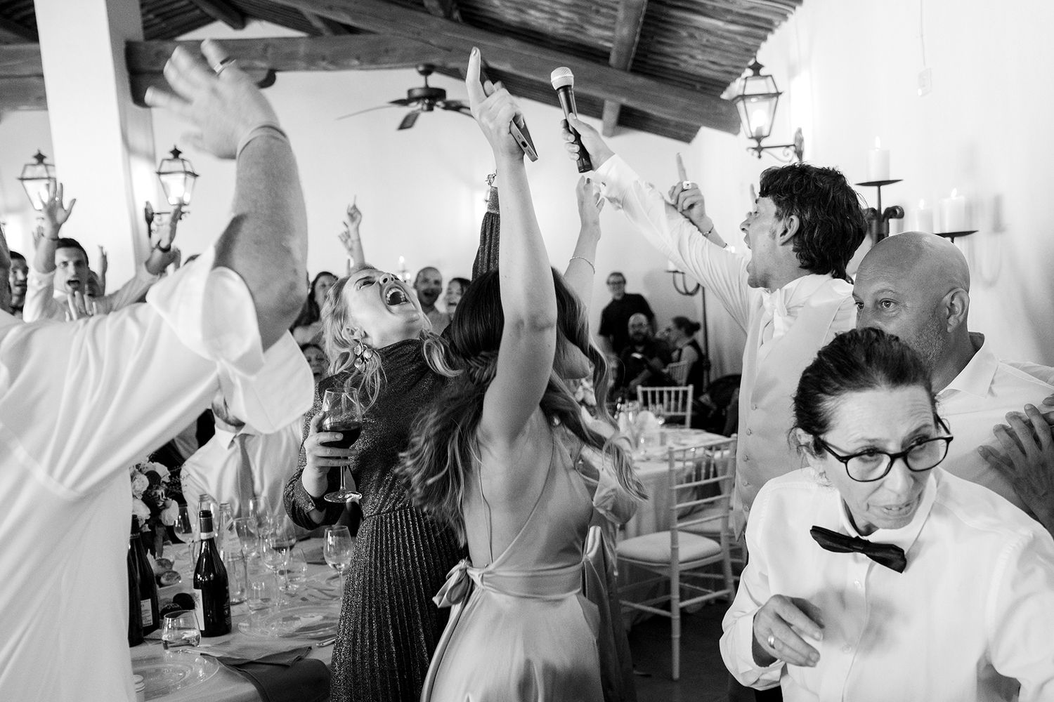 Large group of wedding guests dancing and celebrating with enthusiasm at an indoor reception.