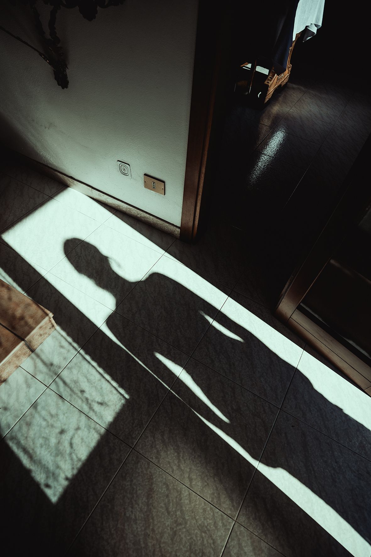 Dramatic shadows cast by sunlight through windows create geometric patterns on a dark floor.