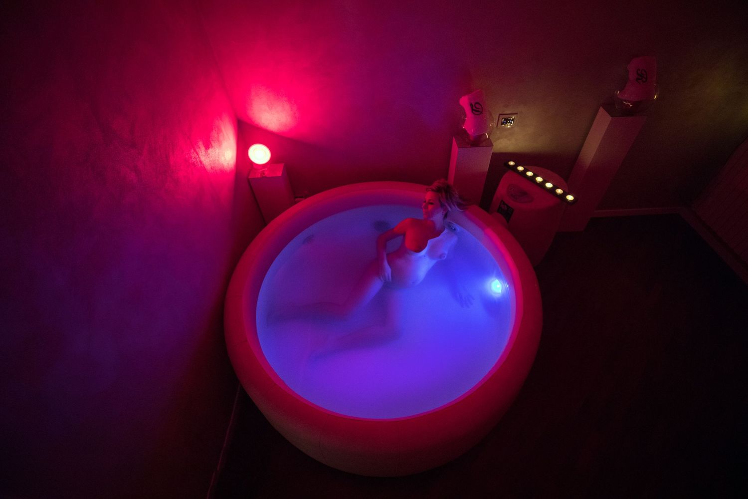 Illuminated hot tub or spa with pink and blue mood lighting creates a dramatic atmosphere.