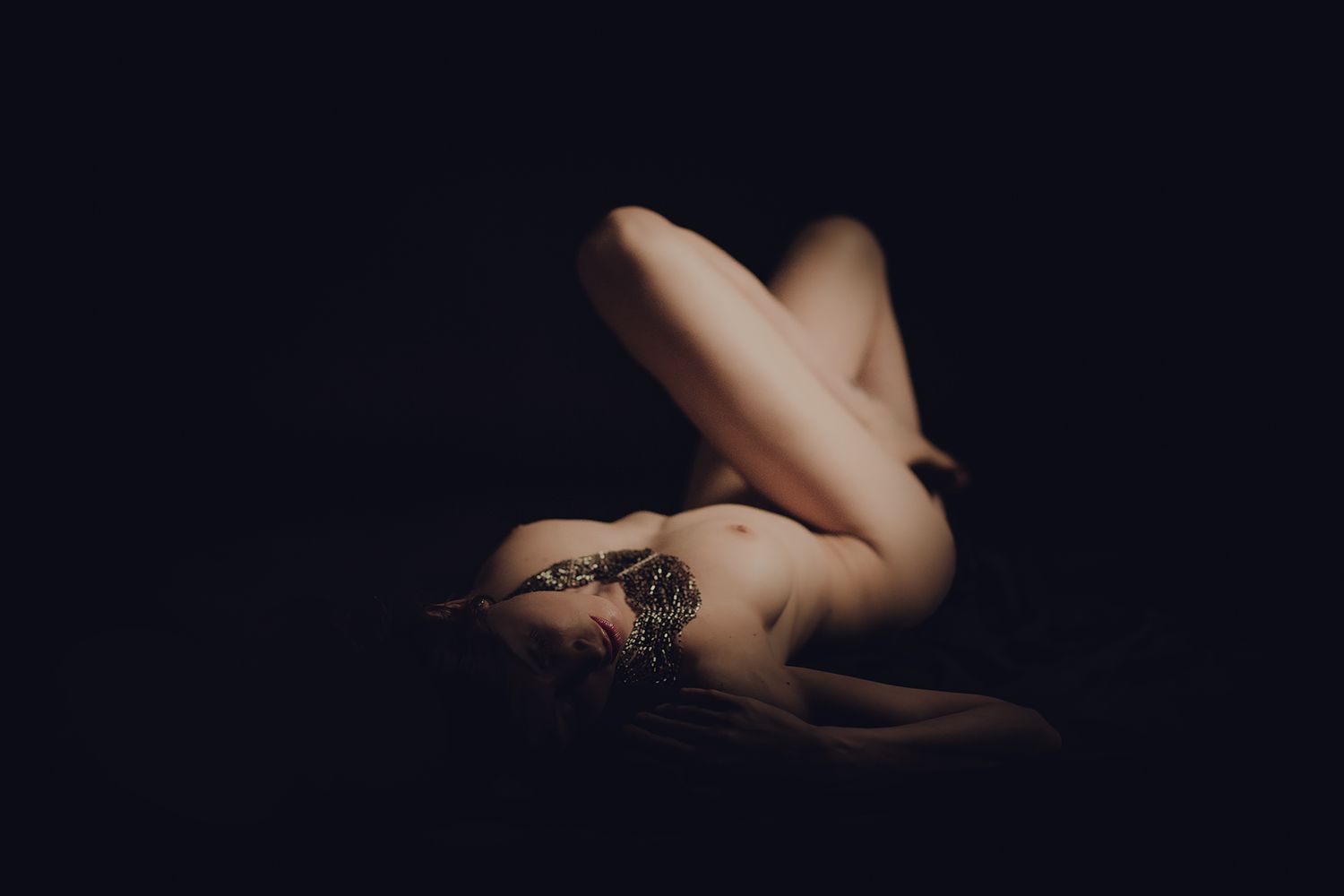 Minimalist nude photography with dramatic shadows and lighting creating abstract shapes.