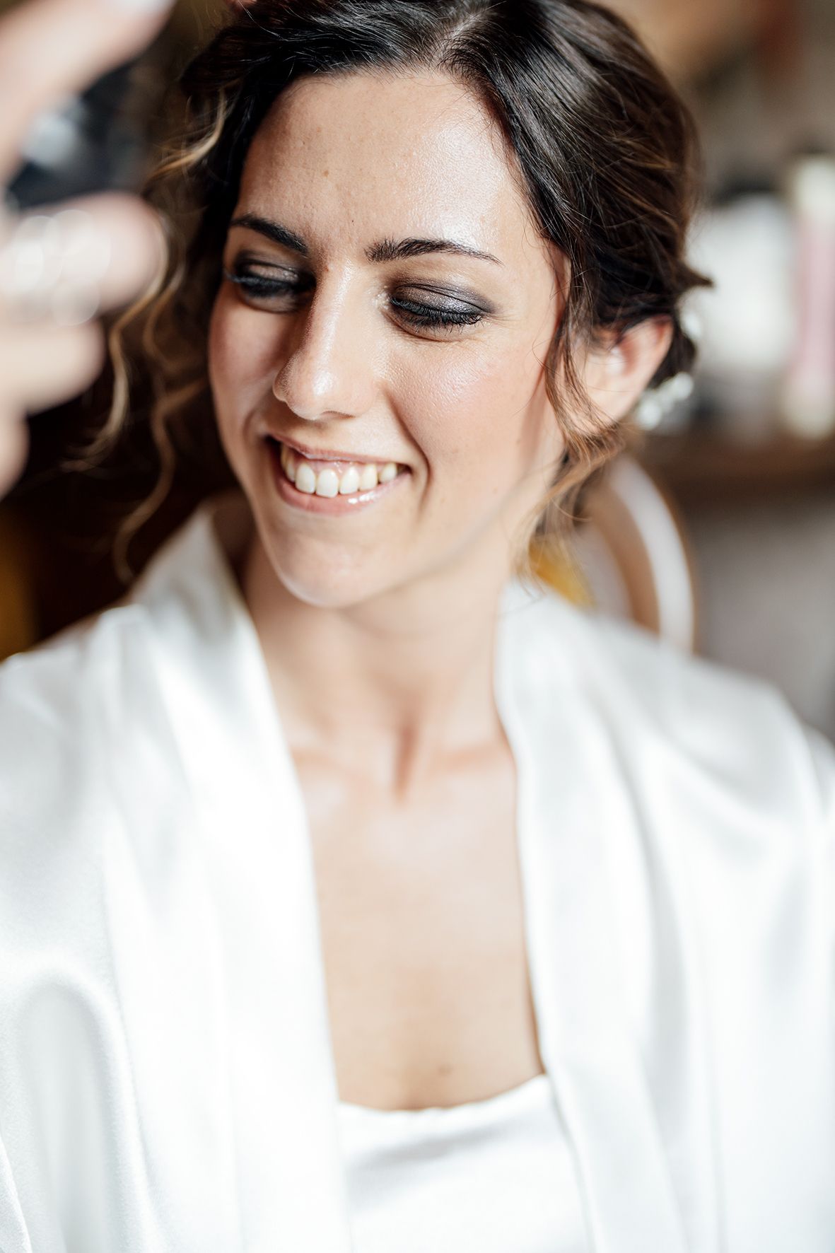 Close-up portrait showing joyful expression and natural makeup in soft lighting.
