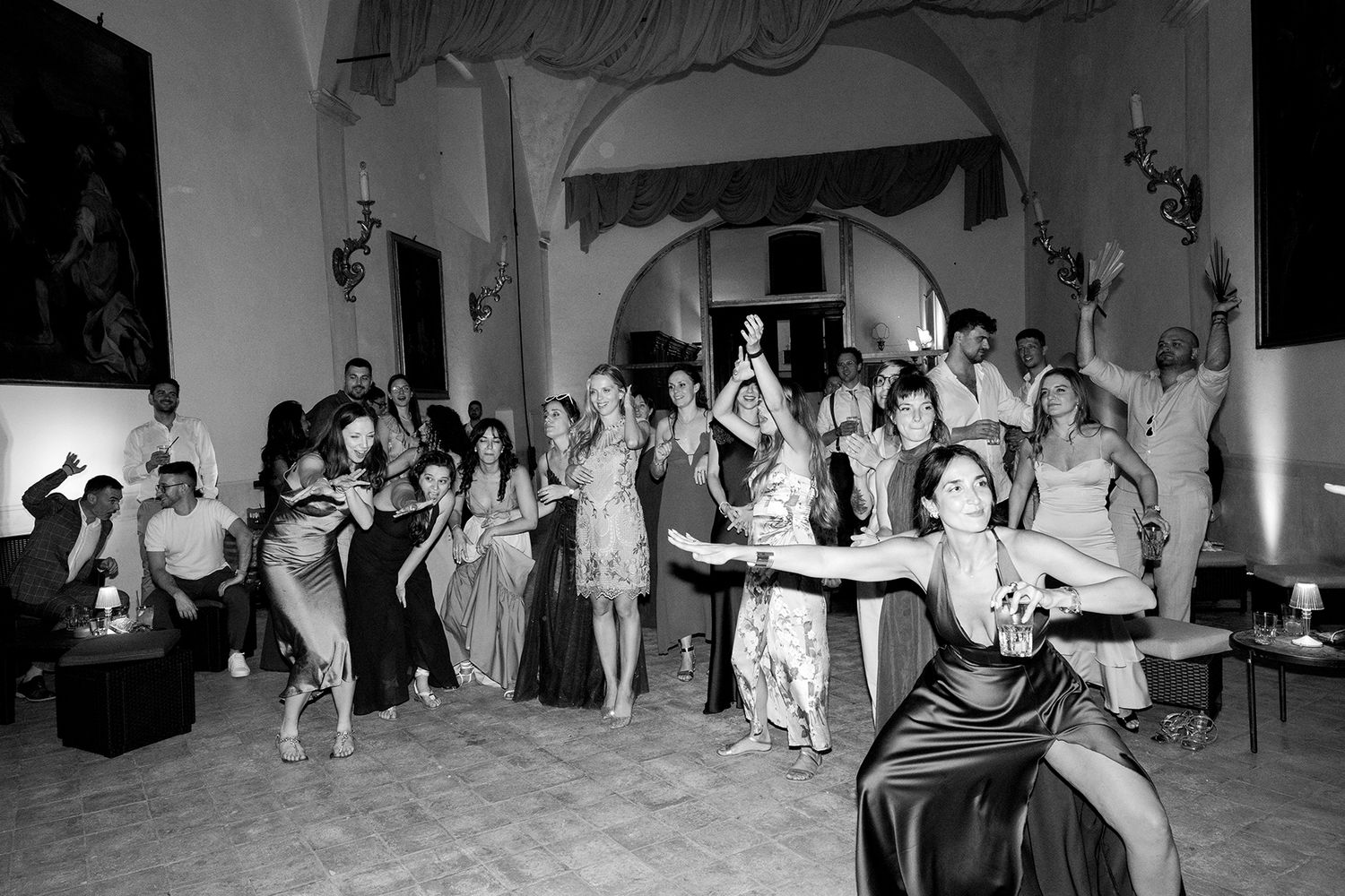 Black and white photos show wedding guests dancing and celebrating at a reception party.