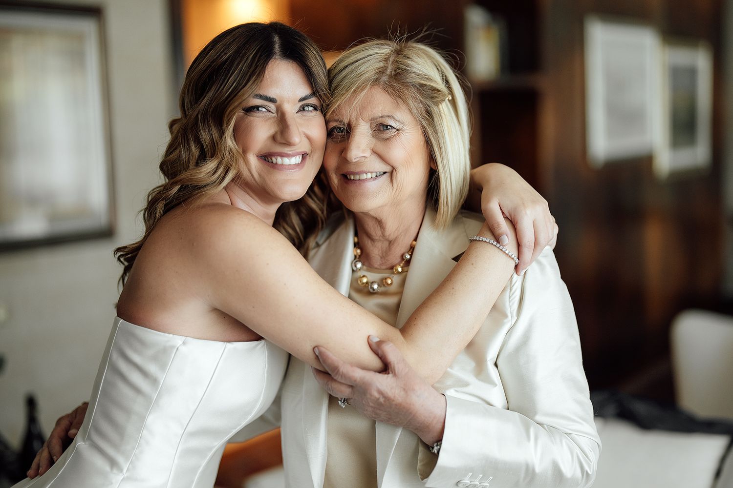 Two people in white dresses embracing during wedding celebration.