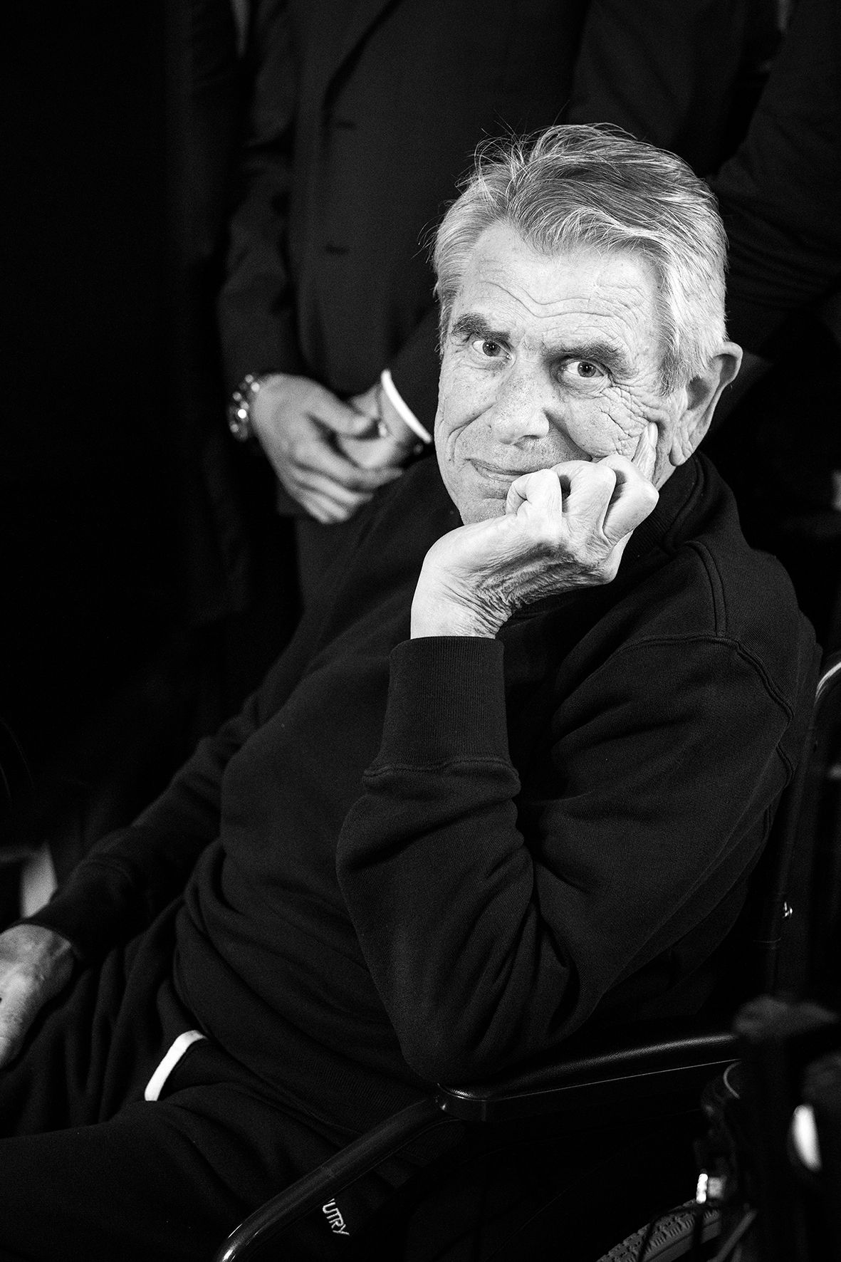 Black and white portrait of an elderly person in contemplative pose with hand on chin.