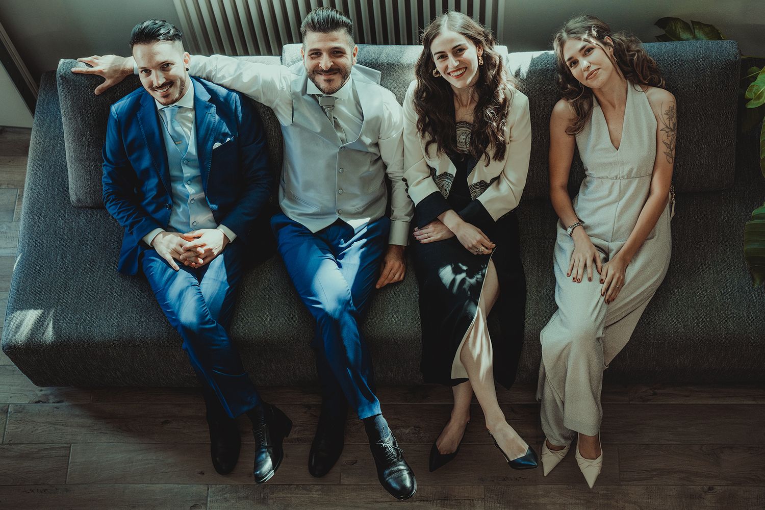 Group of people sitting casually on dark couch in indoor setting.