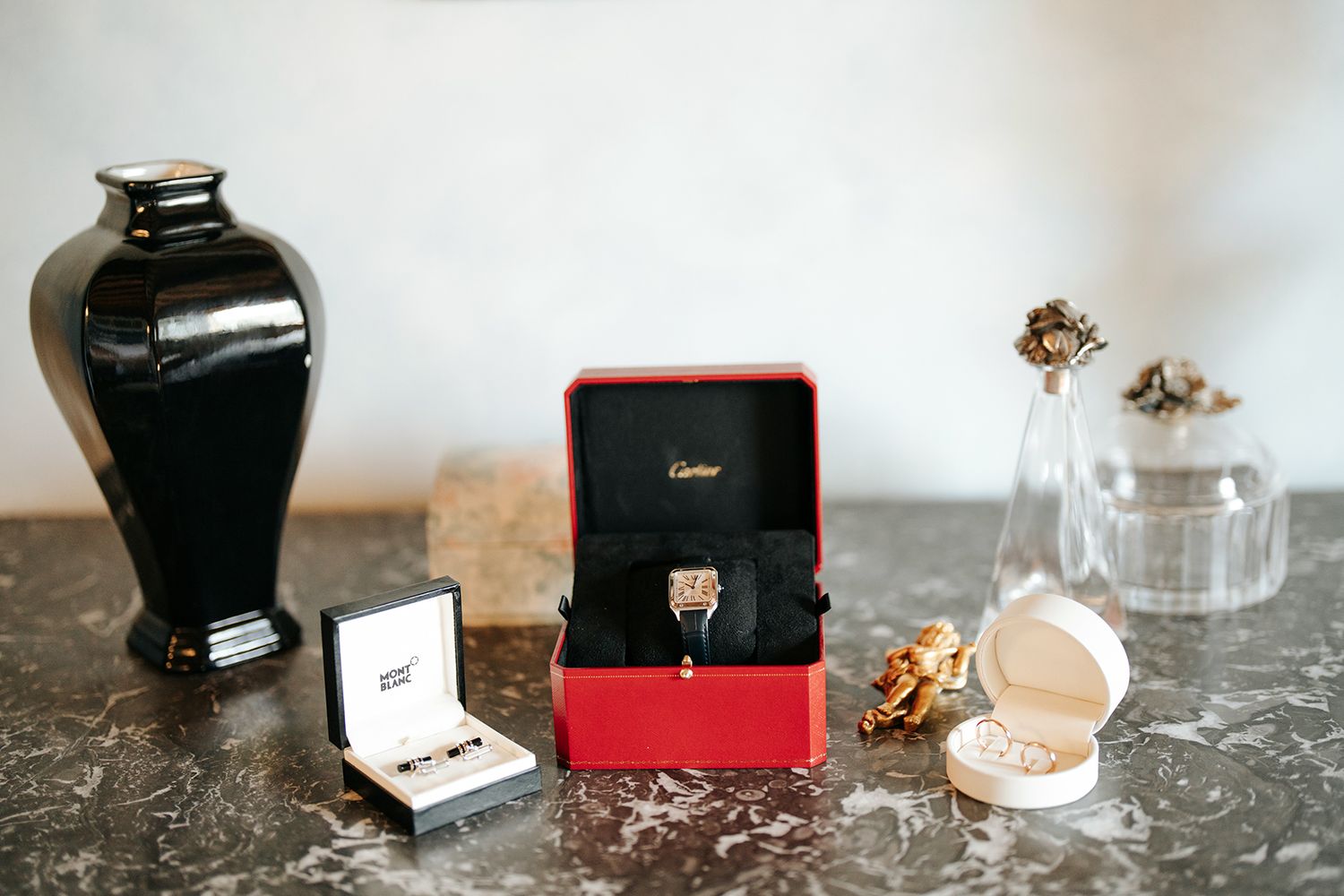 Wedding rings and jewelry boxes arranged on dark marble surface.