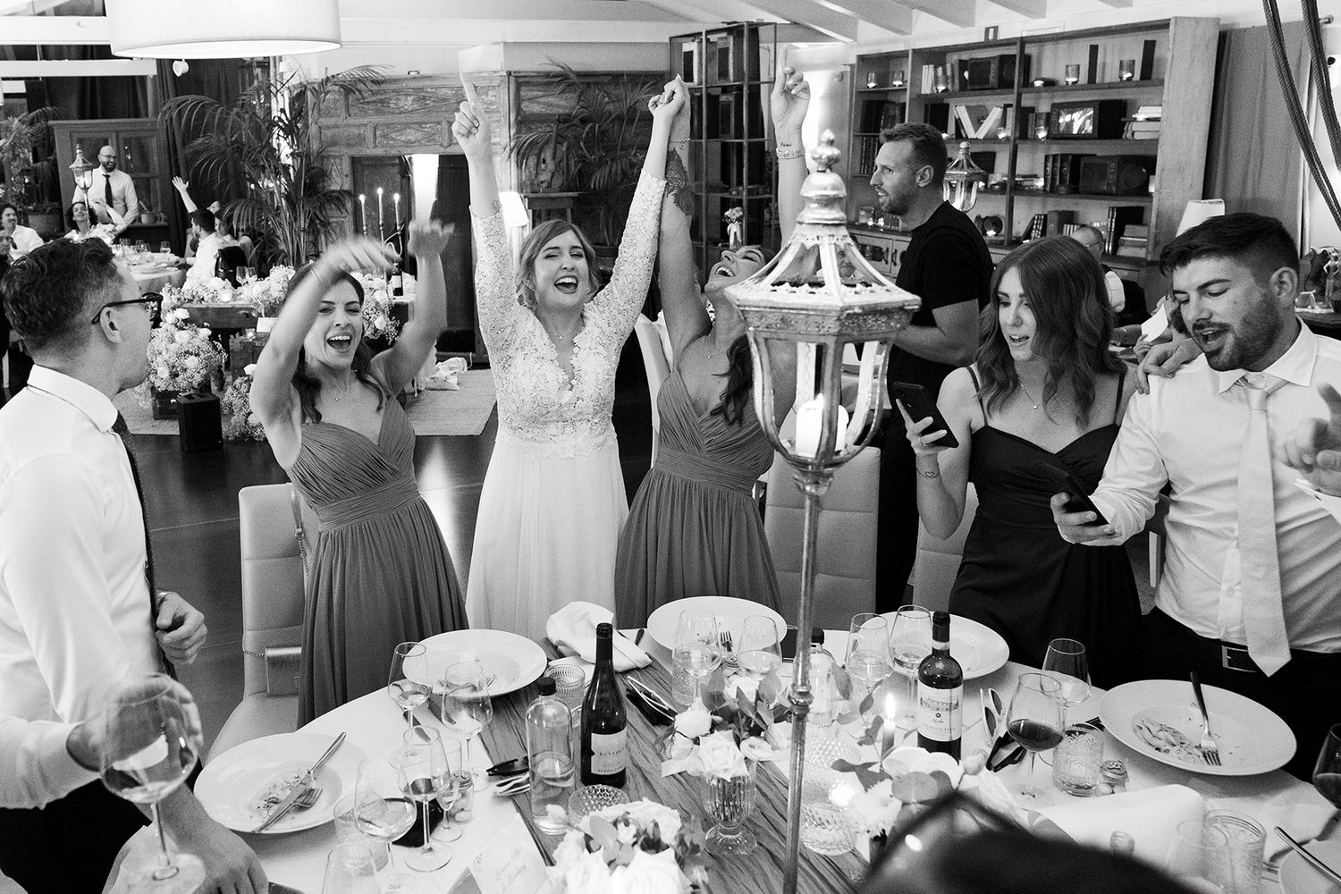 Black and white photo of wedding guests dancing and celebrating at reception.