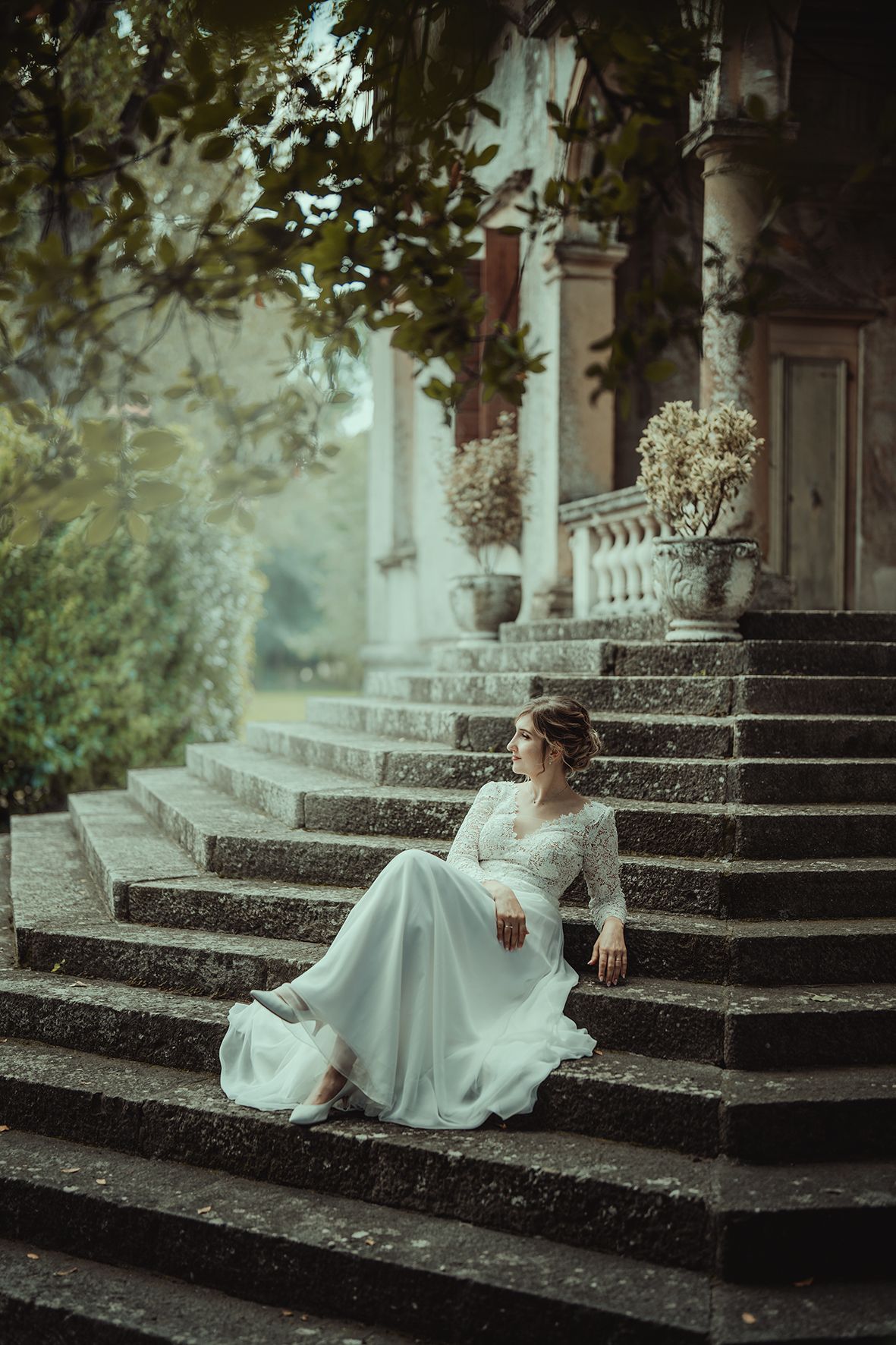 Dreamy bridal portrait on stone steps of historic mansion with lush greenery.