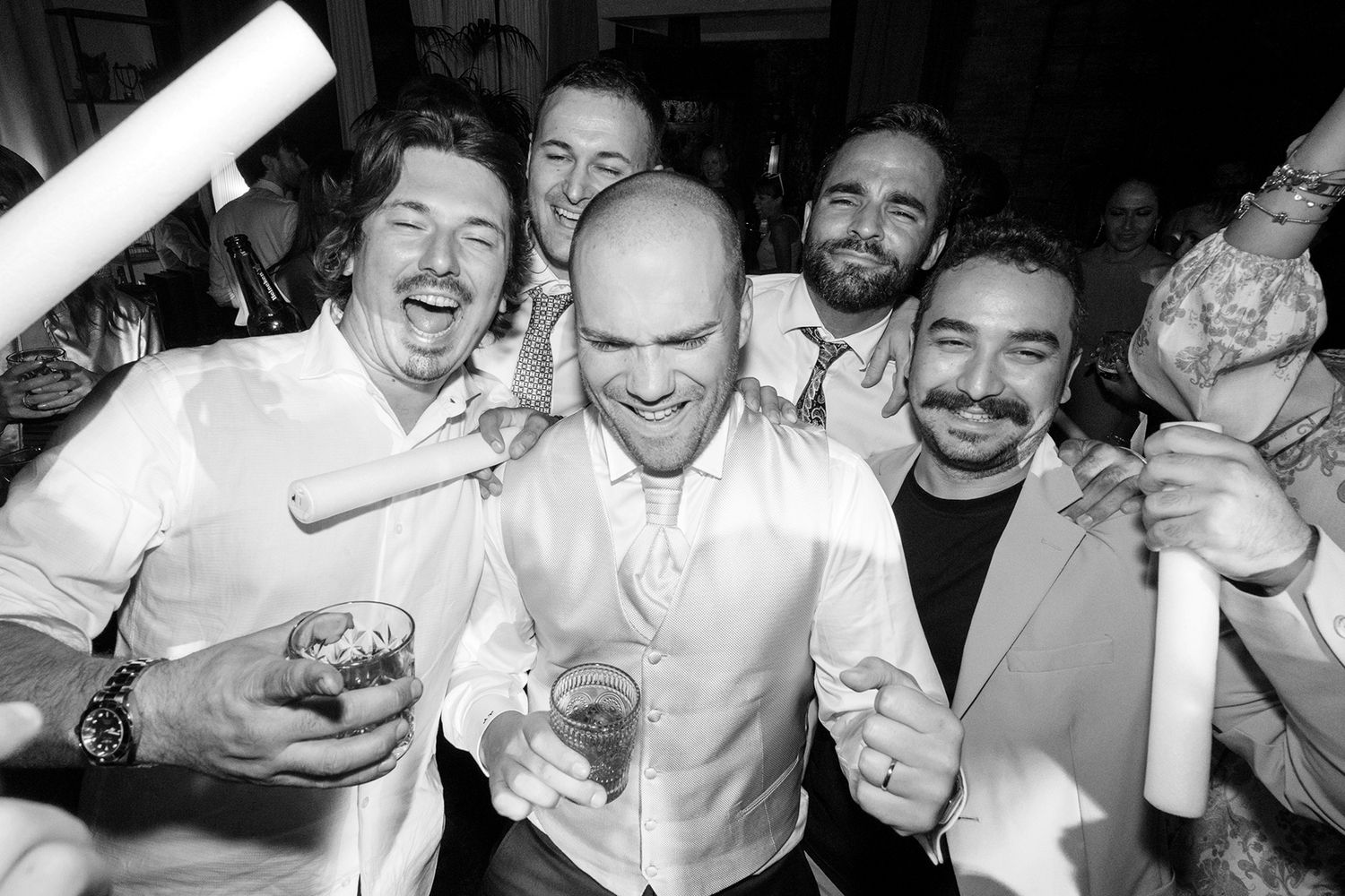 Black and white candid shots of guests laughing and celebrating at a wedding reception.