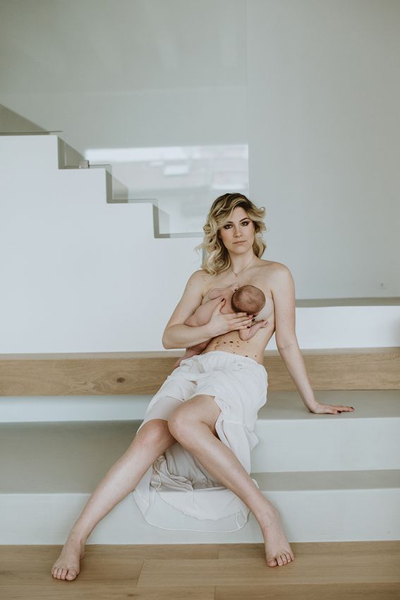 Artistic maternity portrait on white stairs in minimalist setting.