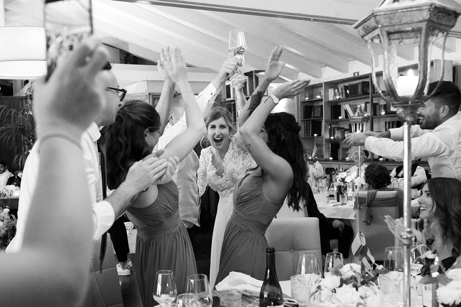 Wedding guests raise their hands in celebration during an energetic reception dance party.