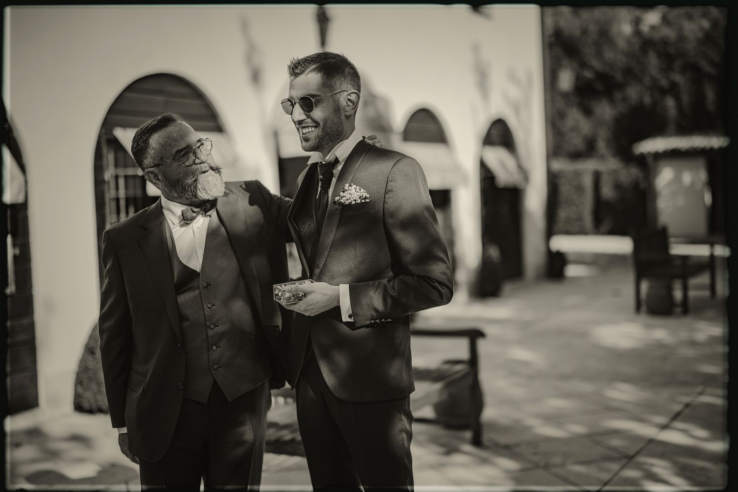 A black and white photo strip showing four candid moments between two people in conversation.