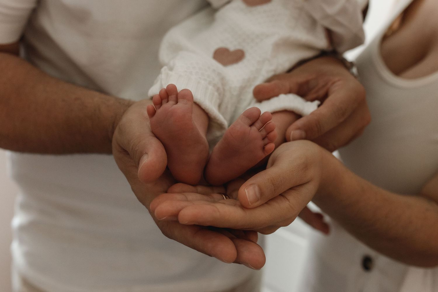 Close-up of tiny newborn feet being held in adult hands.