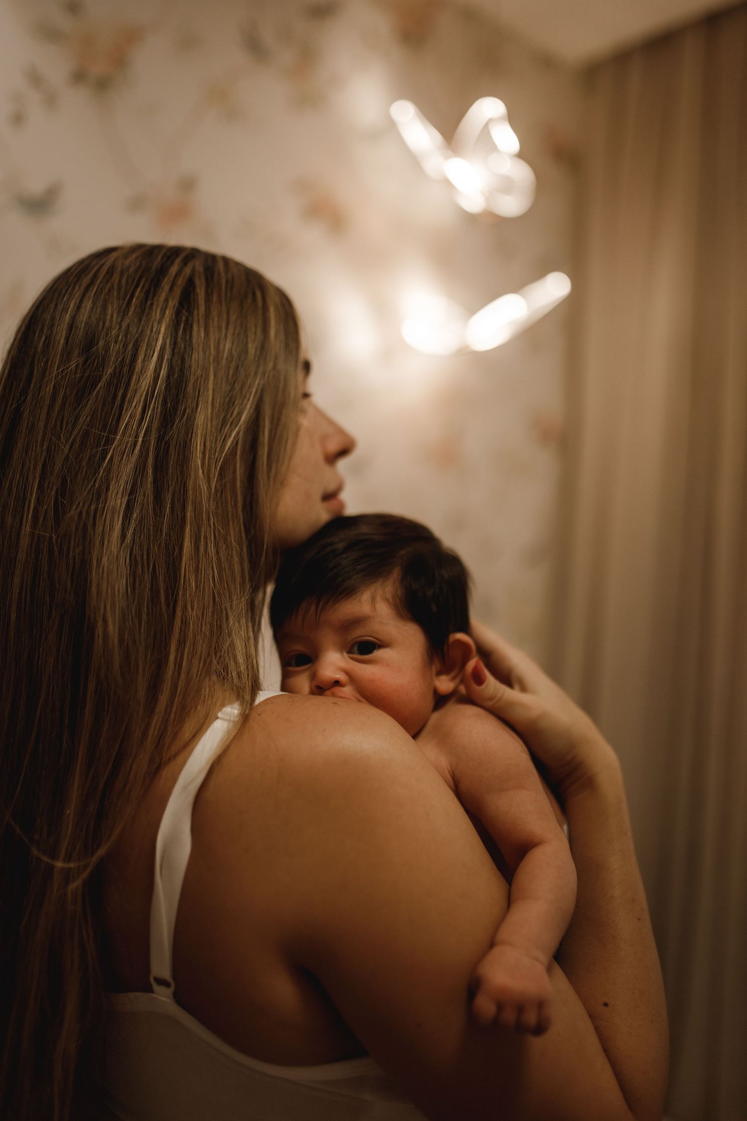 A tender moment captured between a parent and infant with soft butterfly lights in the background.