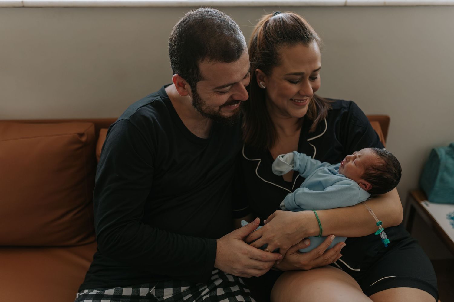 Intimate family moment showing parents bonding with their newborn in warm lighting.