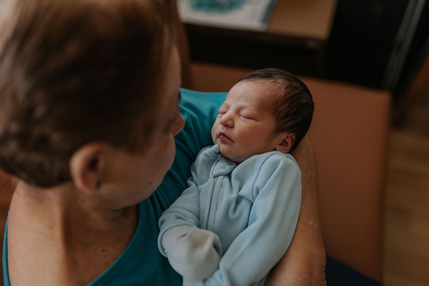 Close-up view of a sleeping newborn baby wearing light blue clothing.