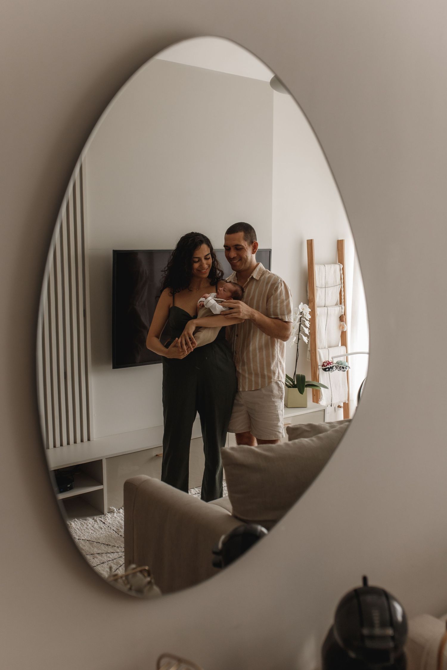 Mirror reflection captures intimate family moment in minimalist home setting.