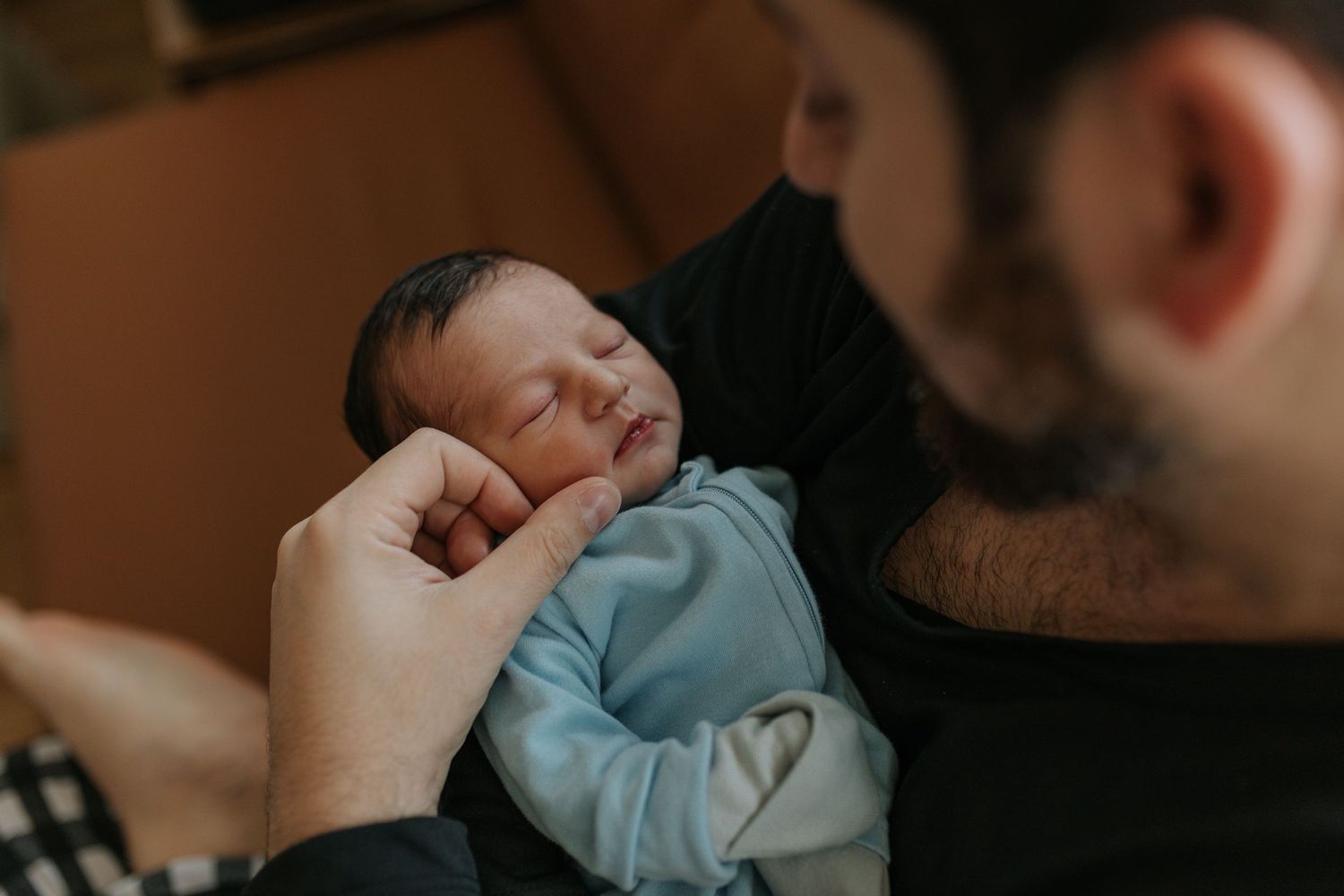 Peaceful scene of a sleeping newborn being held in a home environment.