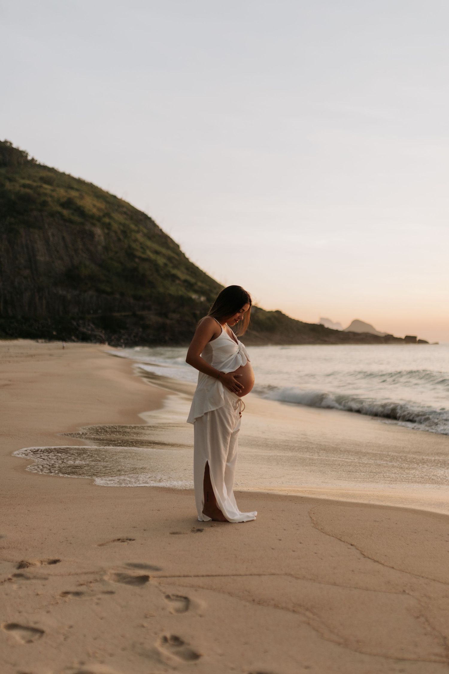 Two people share an intimate moment on a secluded beach with cliffs in the background.