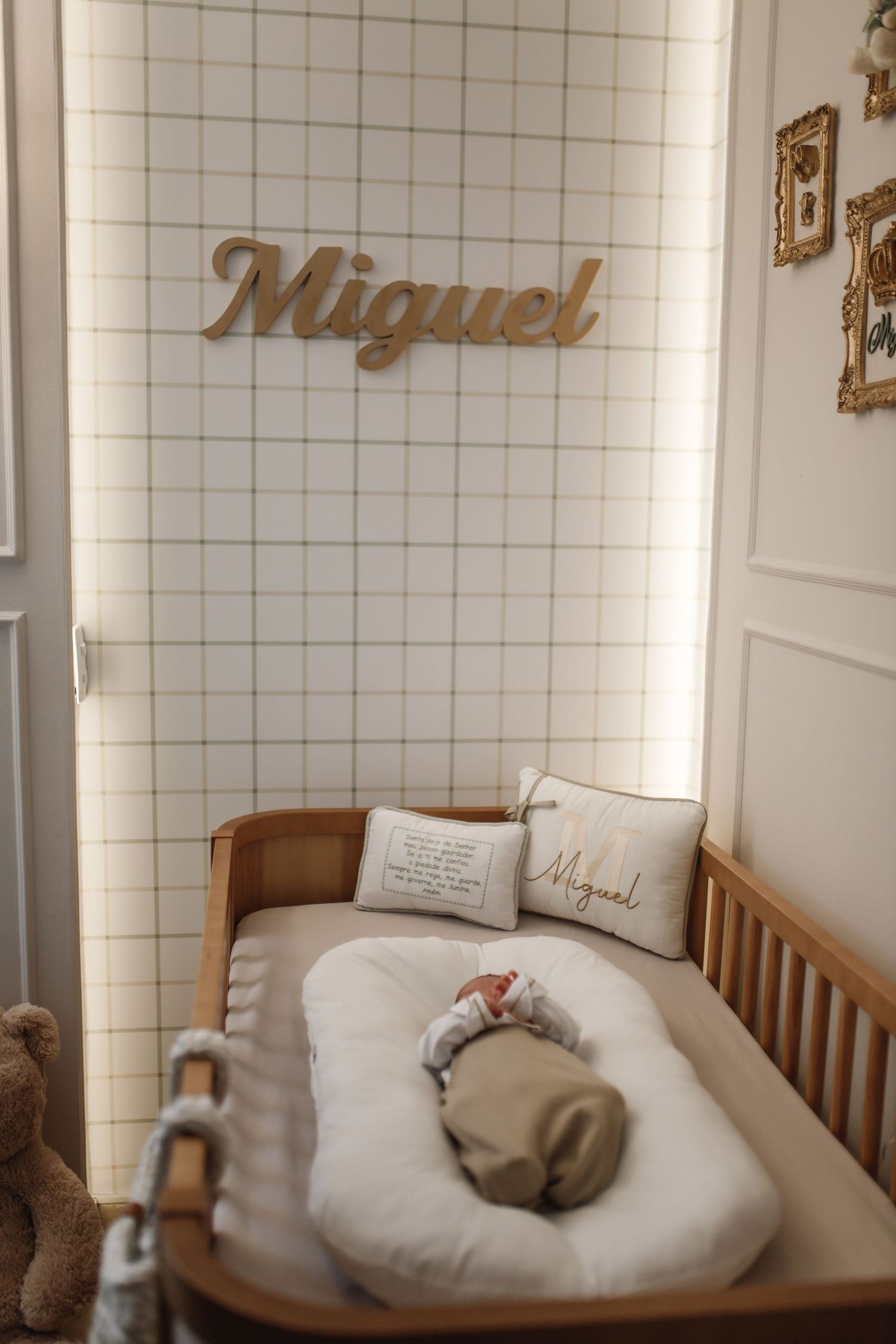 Modern nursery with white tile wall featuring gold name decor and wooden crib.