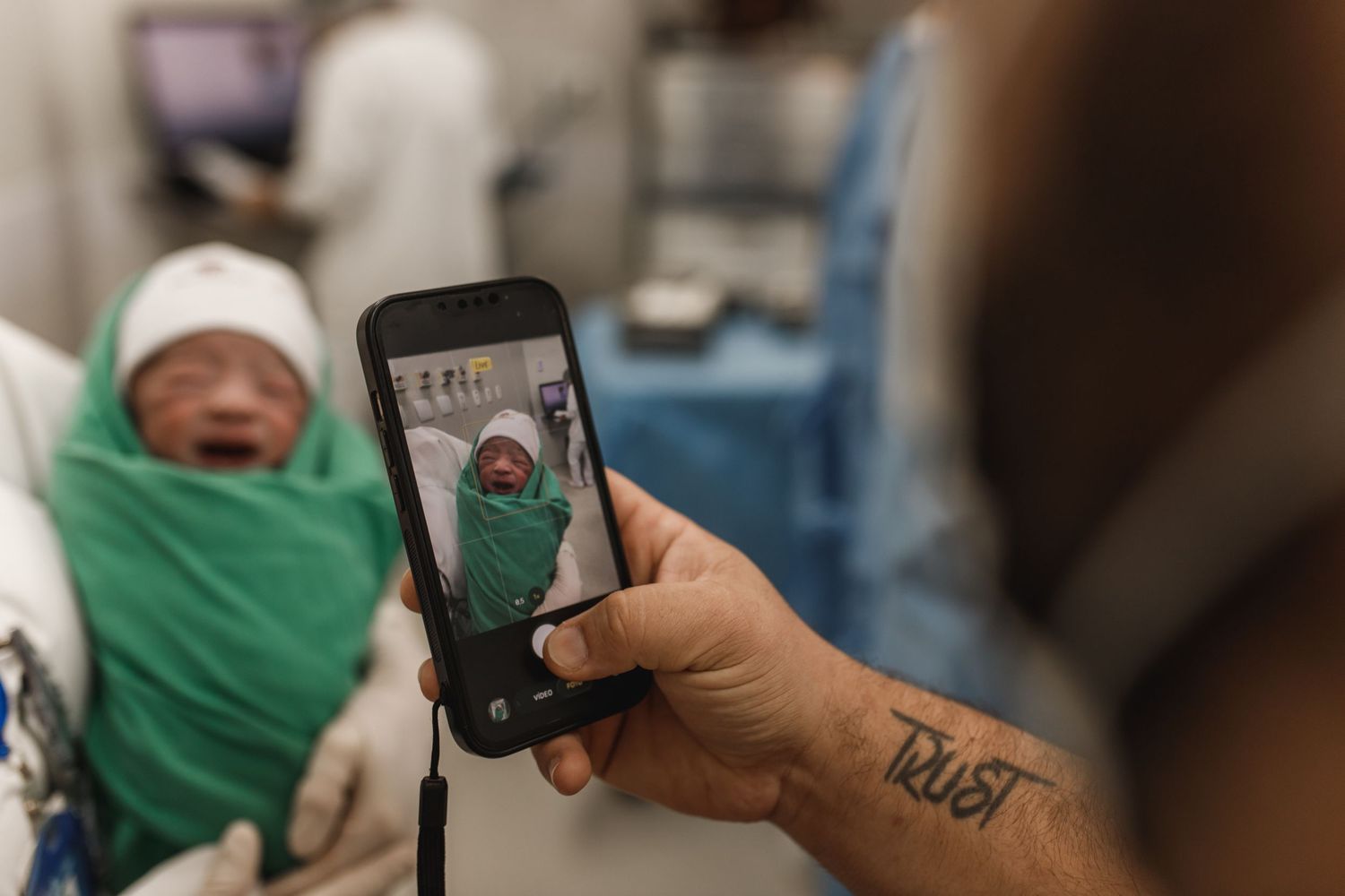 Someone taking photos of a newborn baby with a smartphone in the hospital.