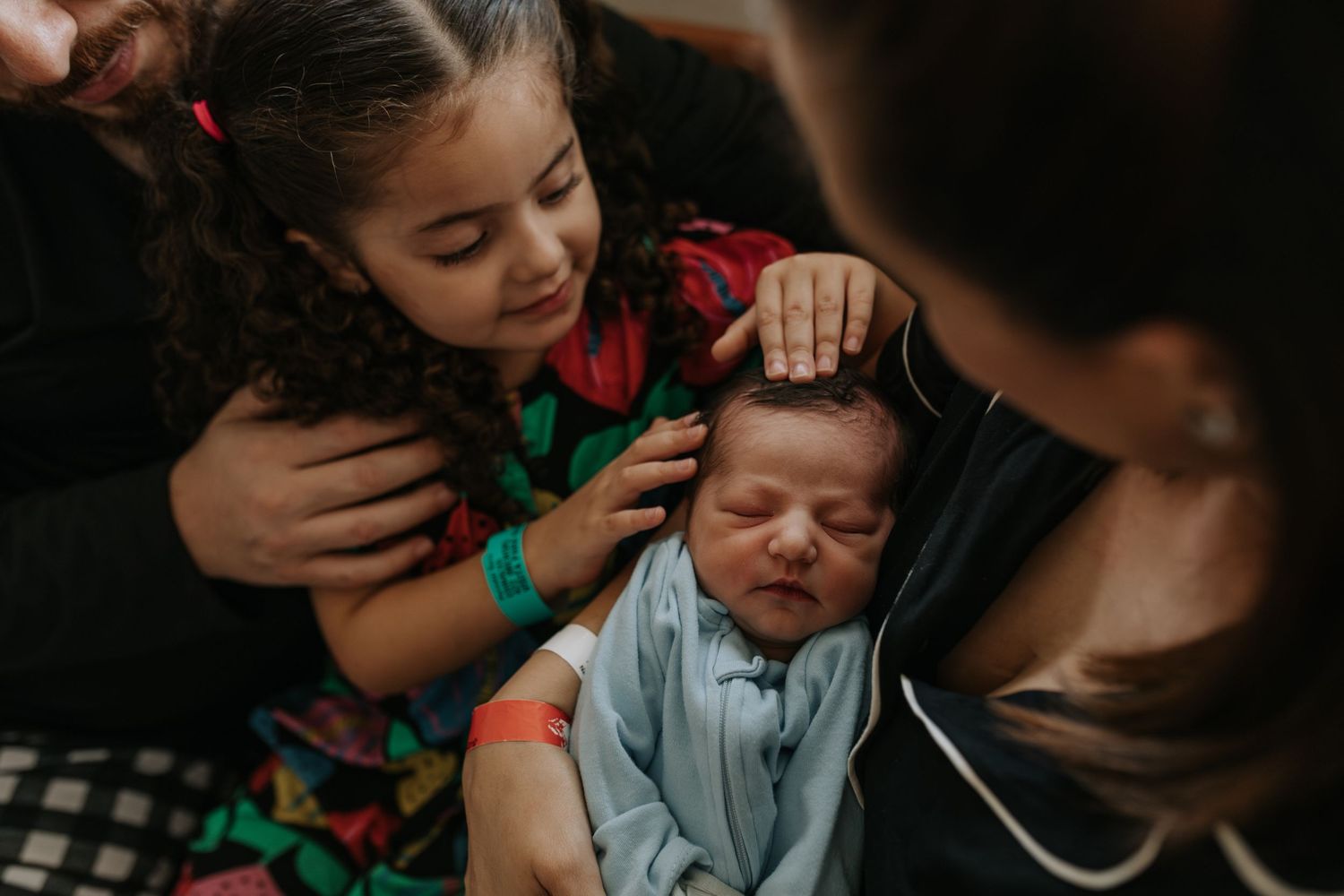 Parents share an intimate moment while holding their newborn baby.
