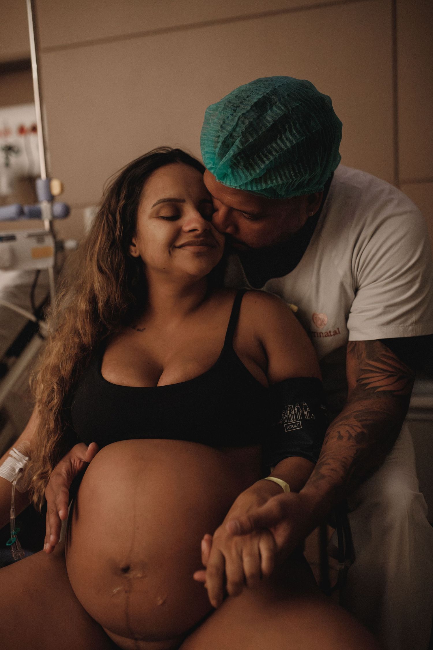 An intimate maternity photoshoot showing a pregnant woman's belly in dim lighting.