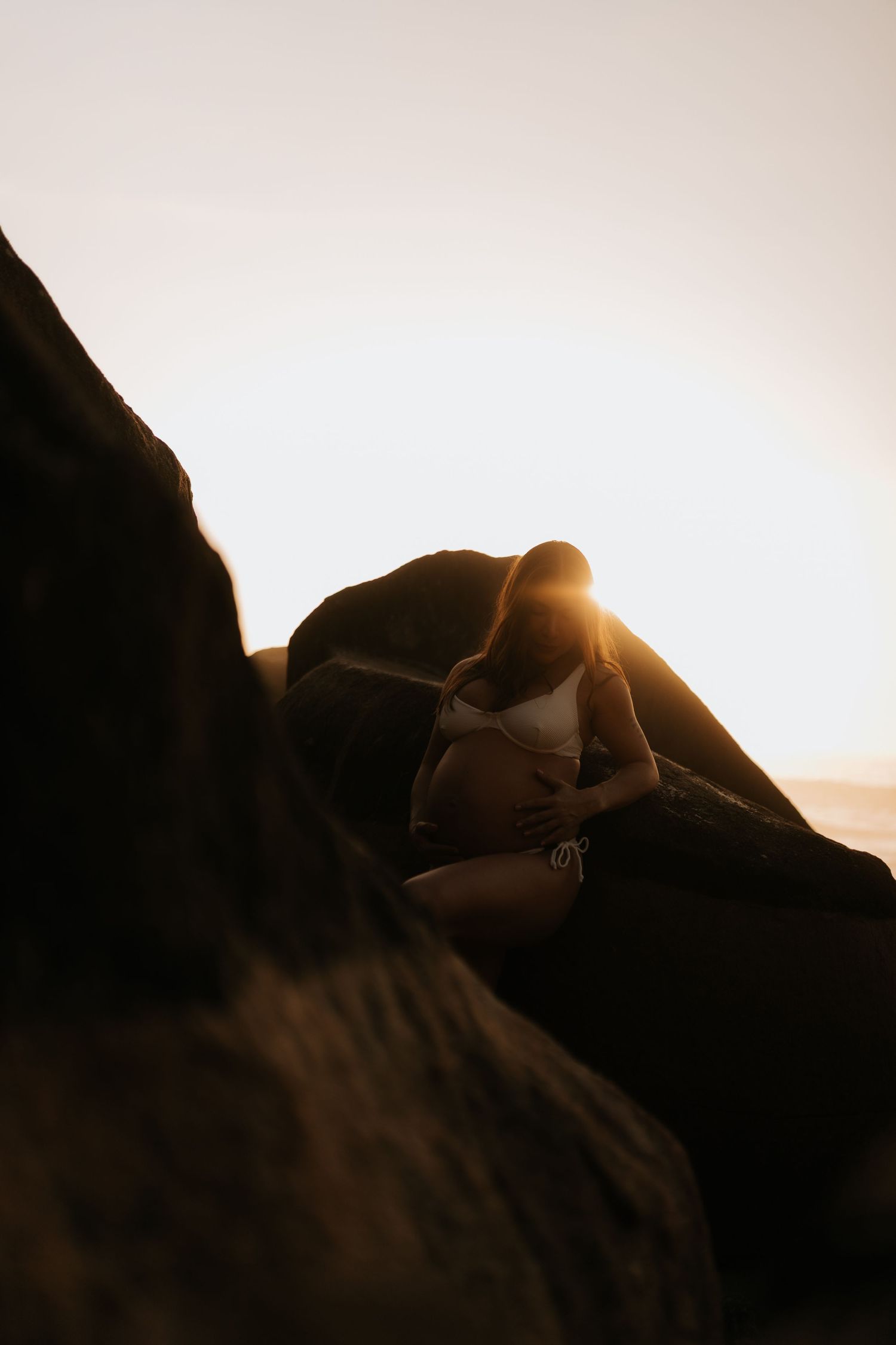Silhouetted maternity photos at sunset with dramatic lighting and shadows.