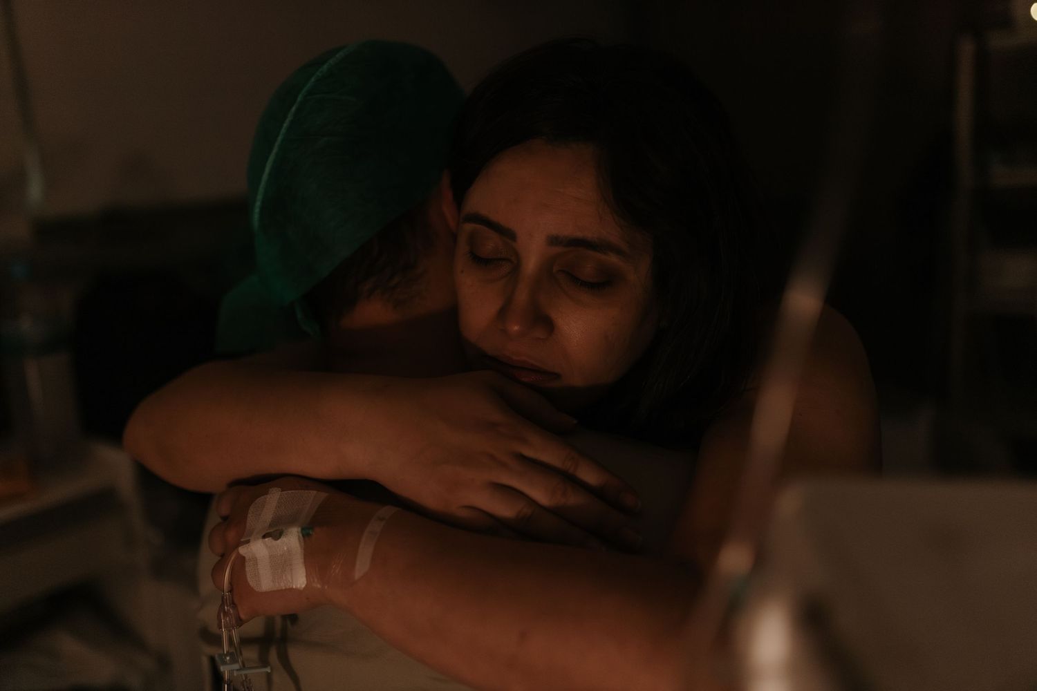 Healthcare provider in scrubs working in a hospital setting with low lighting.