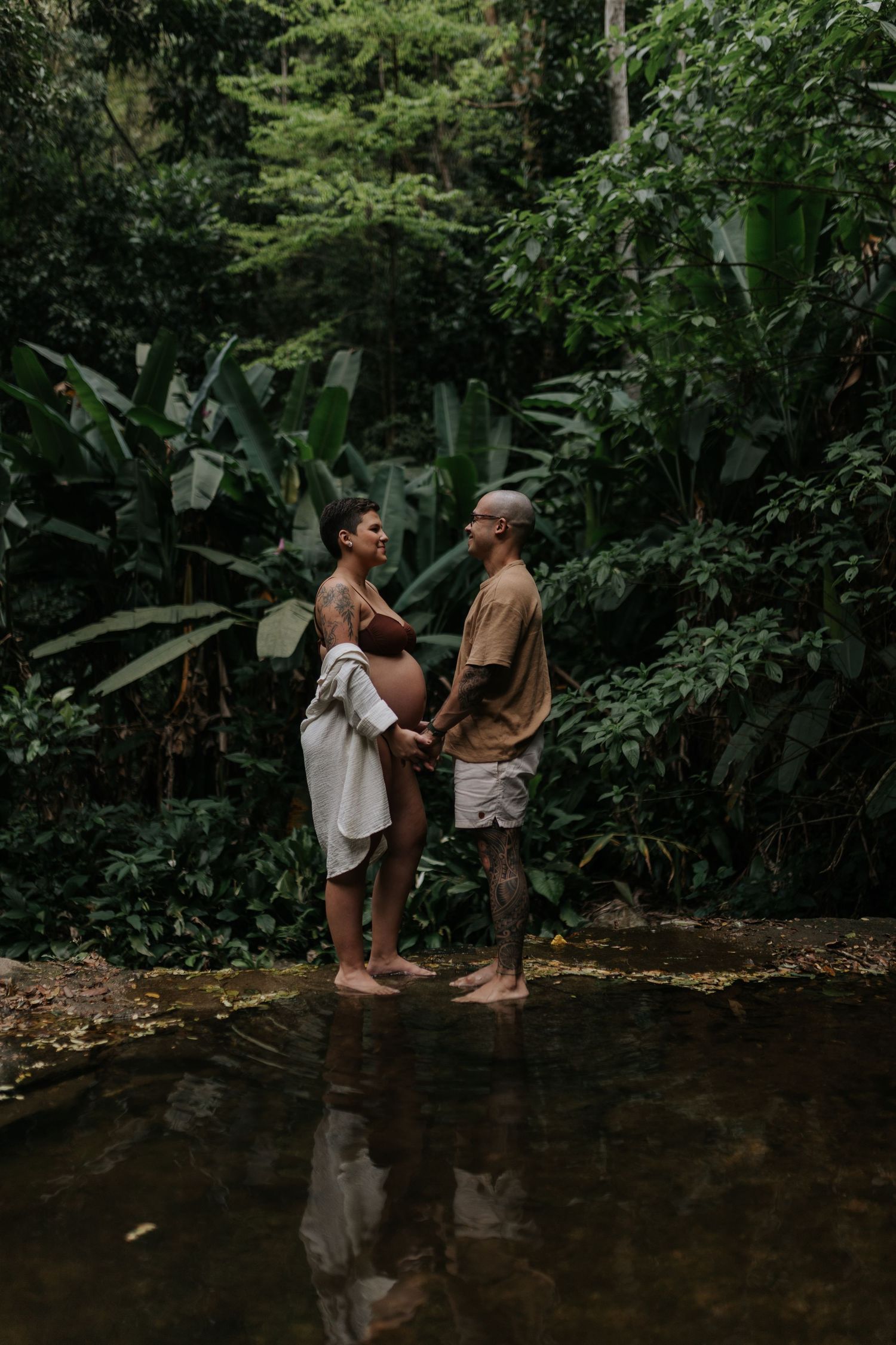 Two people sharing intimate moment while standing in forest stream.