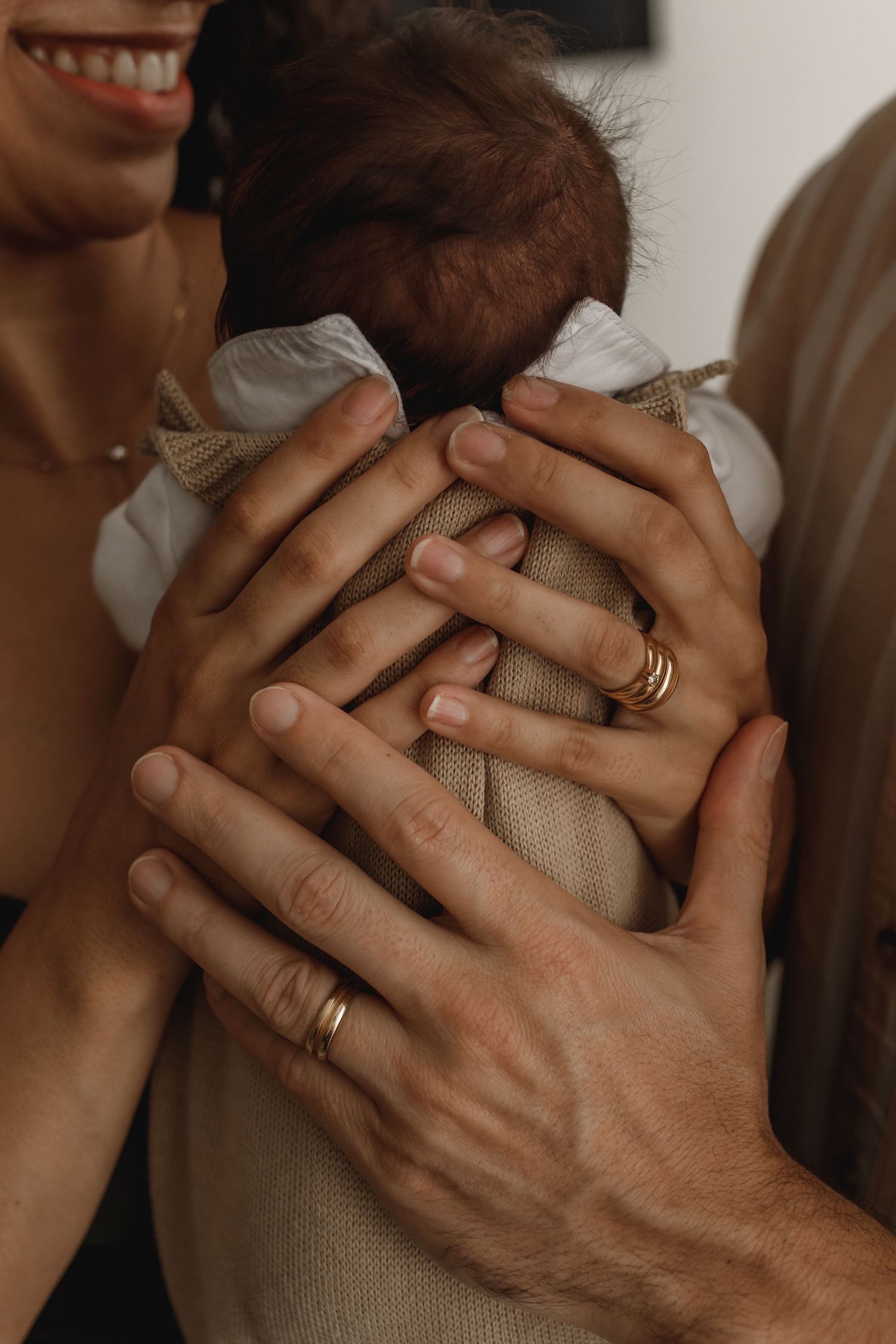 Close-up series of hands embracing tenderly showing wedding rings against a neutral background.