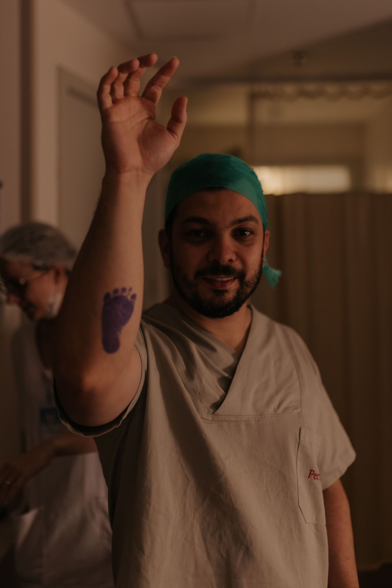 Medical staff in white uniforms and green scrub caps celebrating in a hospital corridor.