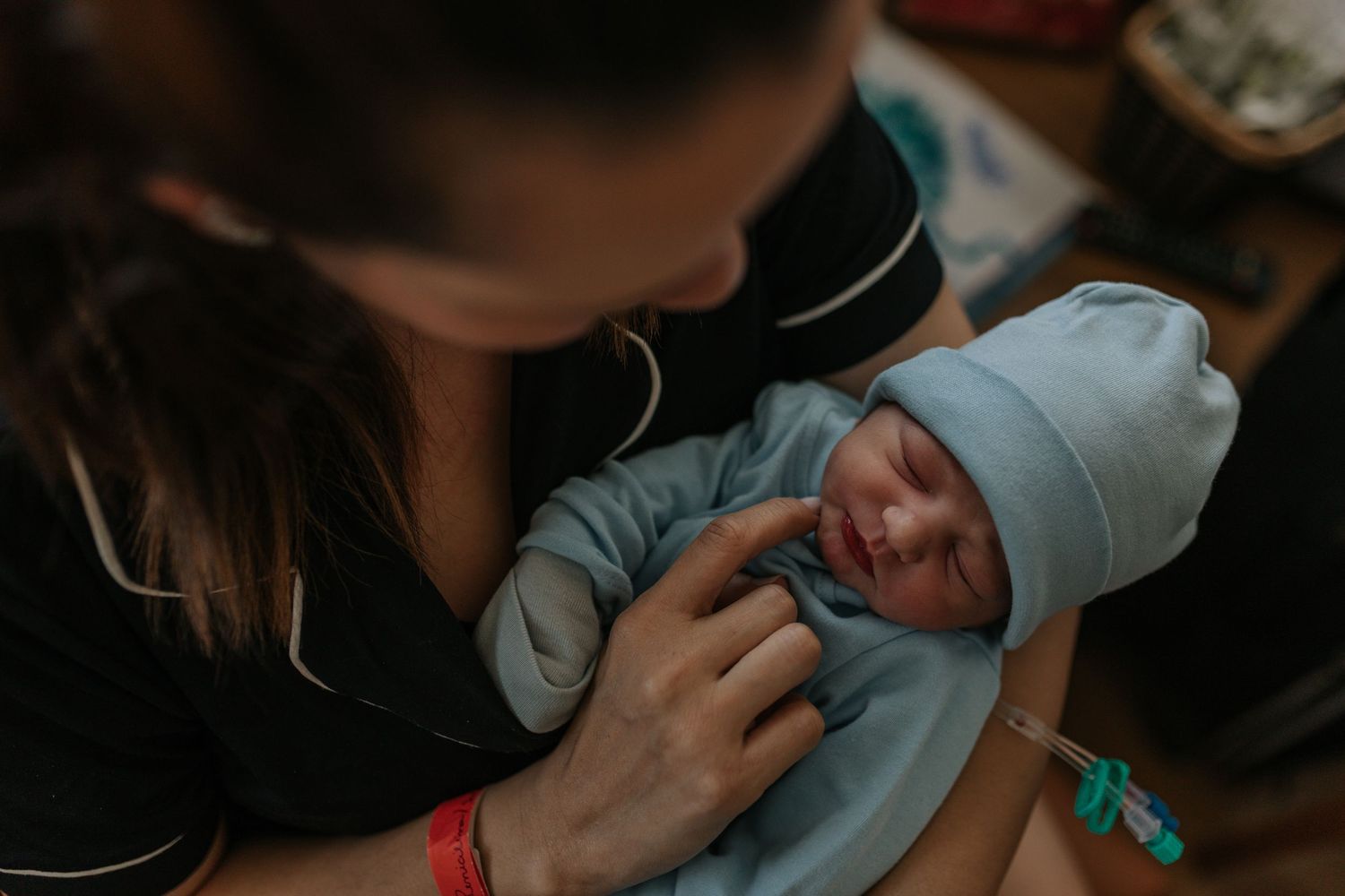 Parents lovingly cradle their newborn baby while sitting together on a couch.
