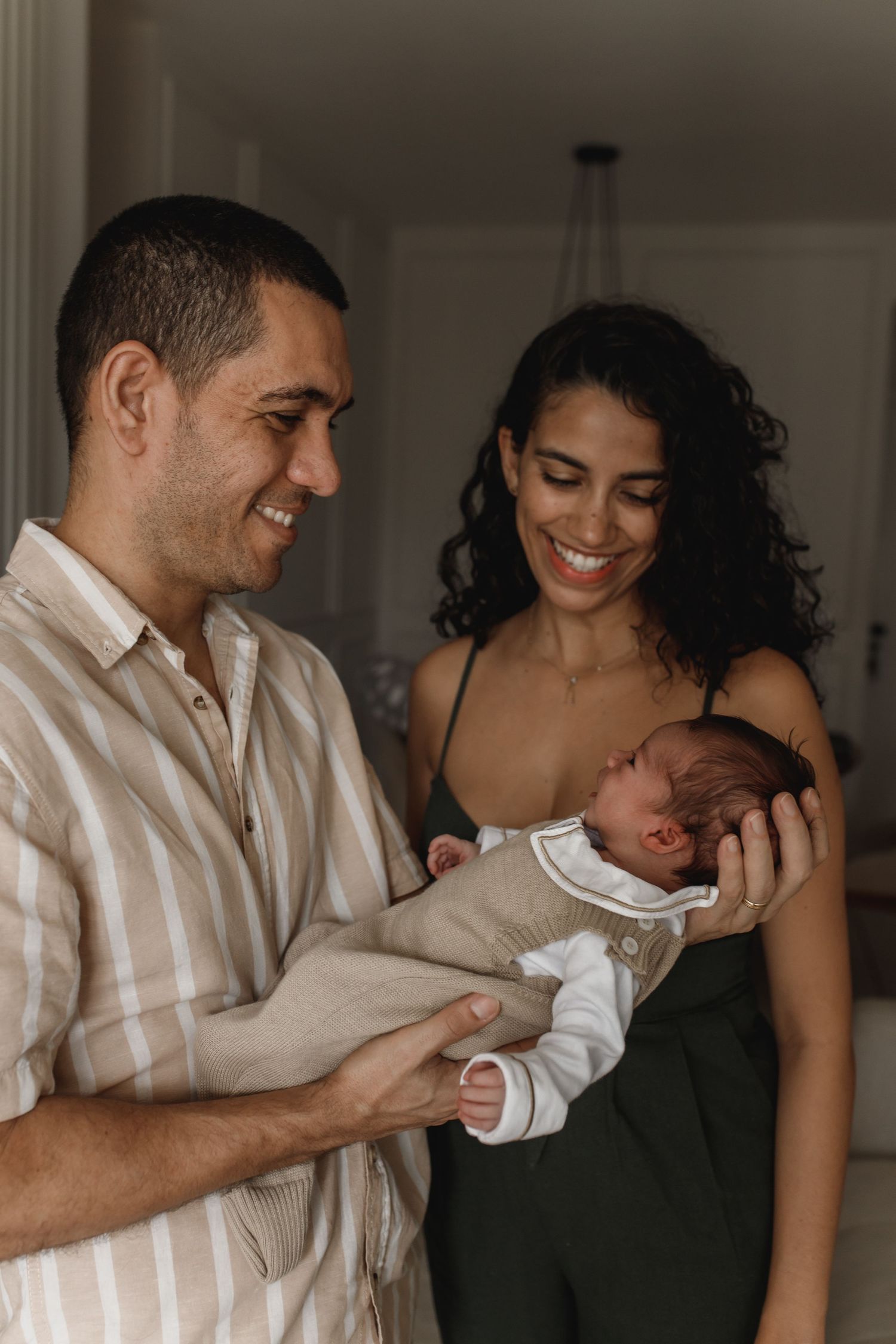 Candid family moments captured in soft window light against neutral decor.