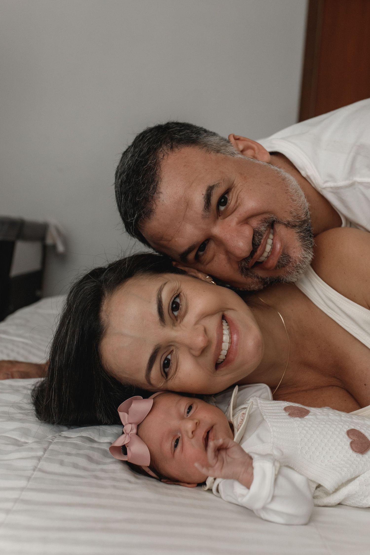 Intimate family moment captured on white bedding.