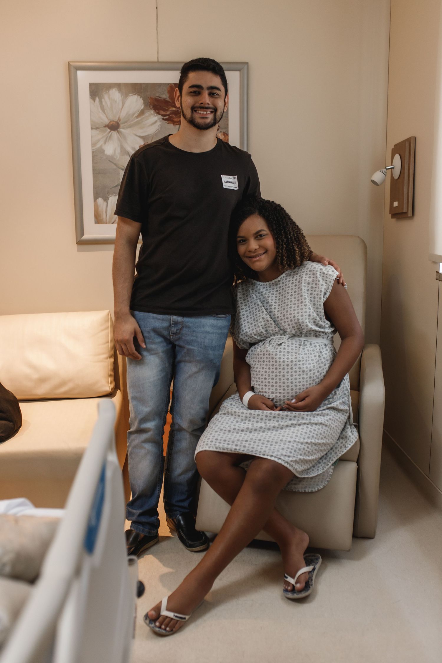 Expectant couple sitting together on a hospital bed during a prenatal visit.