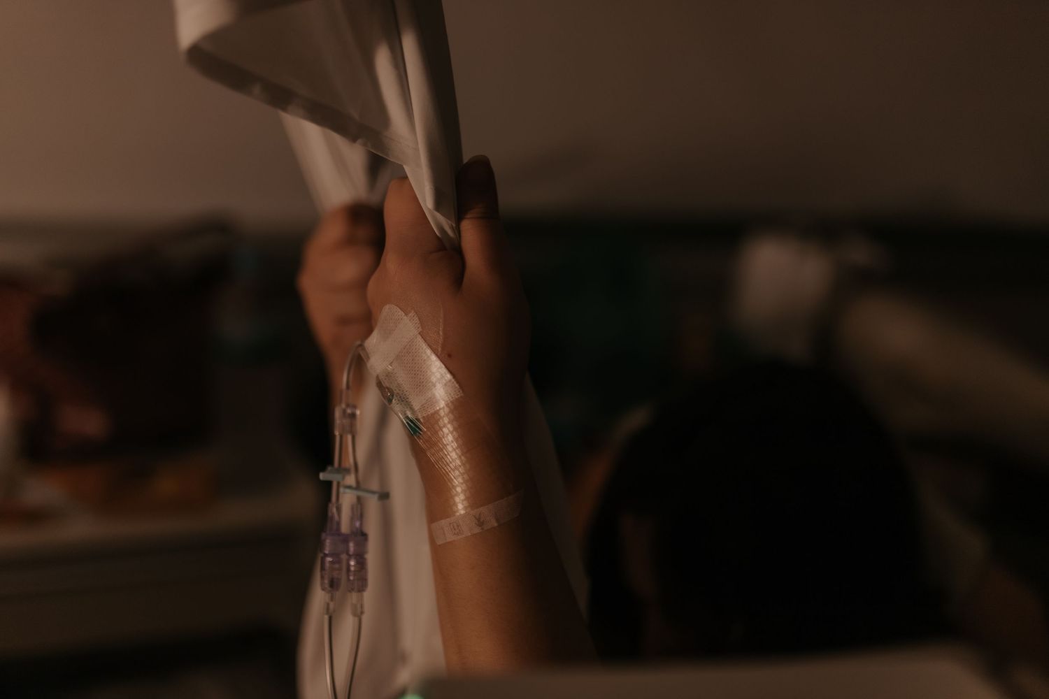 Medical staff preparing equipment in a dimly lit hospital room.