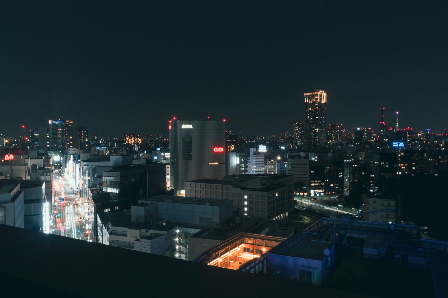 Panoramic nighttime cityscape showing illuminated buildings and urban lights.