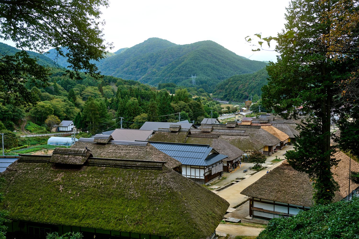 Panoramic view of traditional Korean village houses with tiled roofs nestled in green mountains.