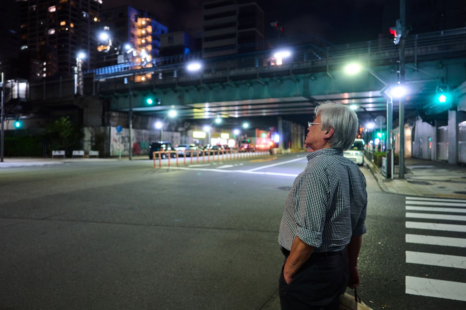 Empty city street at night with traffic lights and buildings illuminated in the distance.