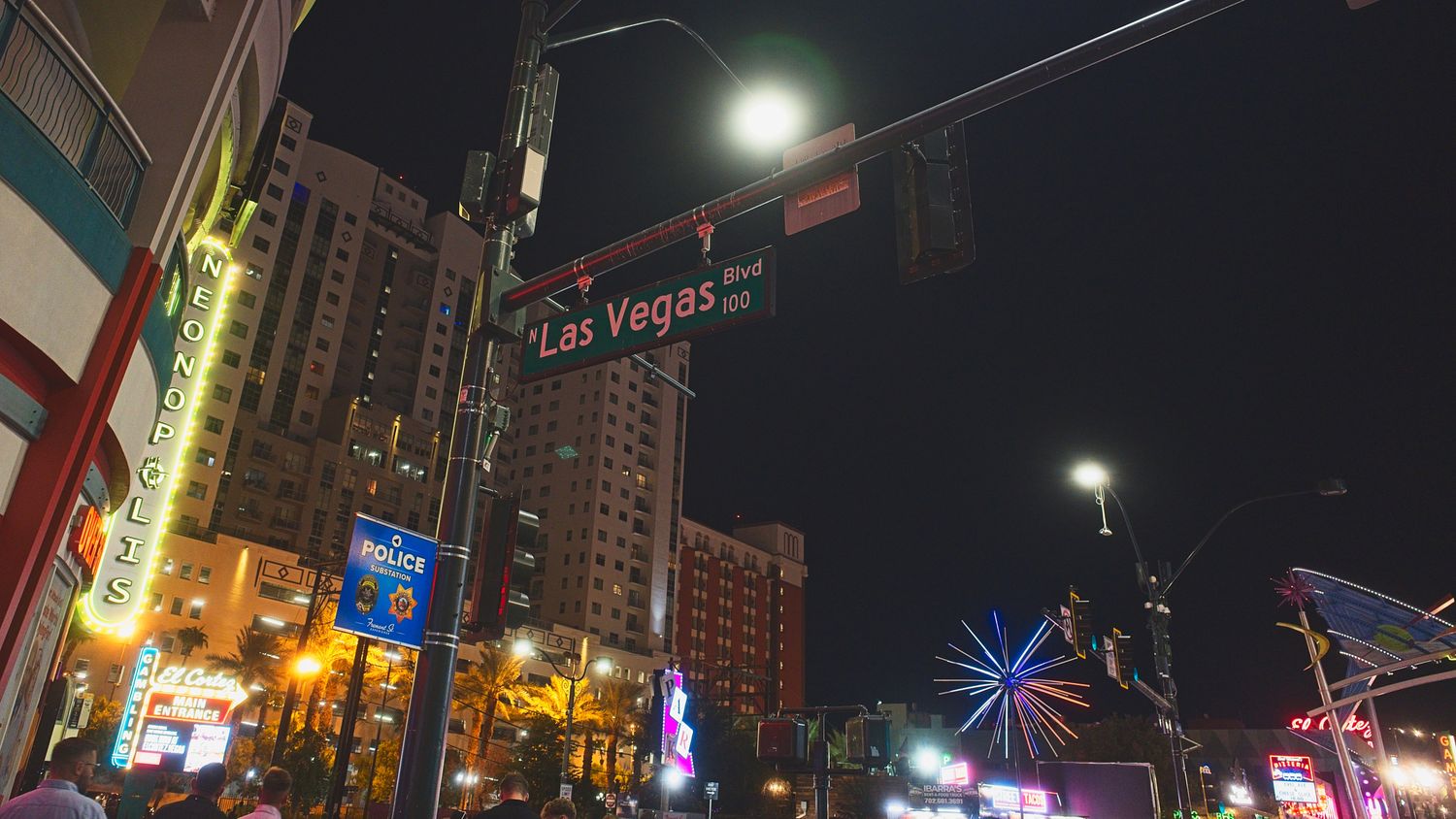 Illuminated city street at night with bright neon signs and tall buildings in Las Vegas.