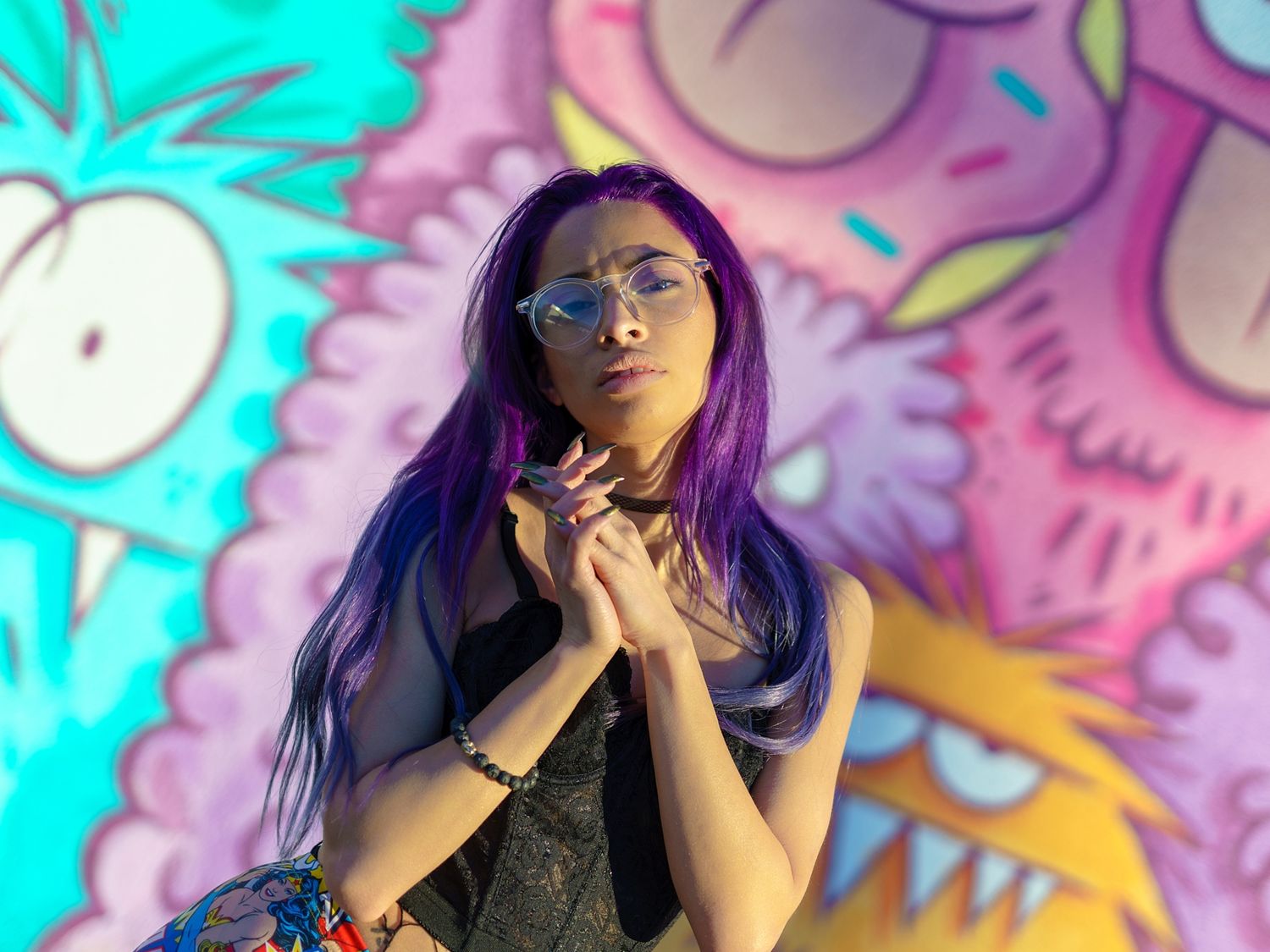 Artistic portrait against colorful graffiti wall with turquoise and pink tones.