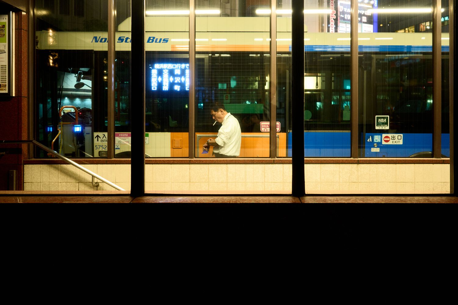 Modern office building exterior at night with illuminated windows creating a grid pattern.