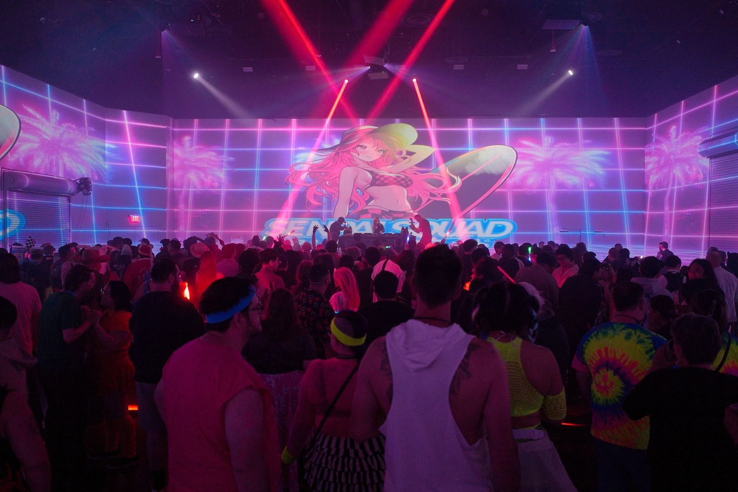 Large concert crowd under purple and pink lighting with geometric grid patterns on display.