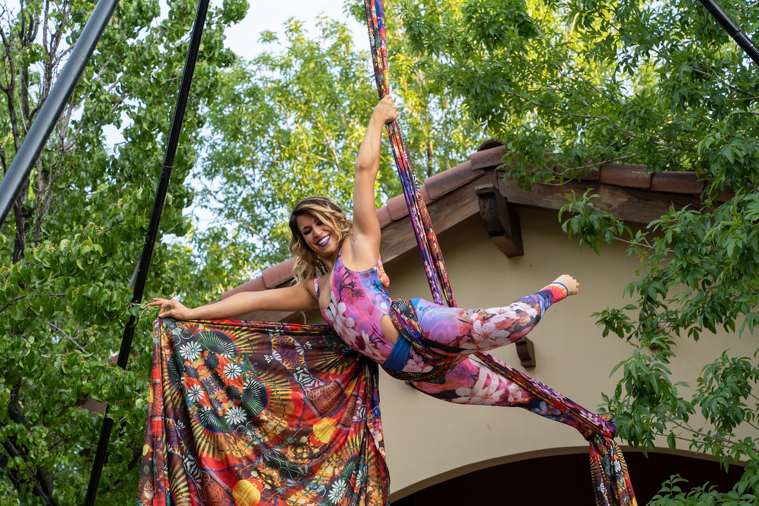 Dancer in colorful floral dress performing outdoors among trees.