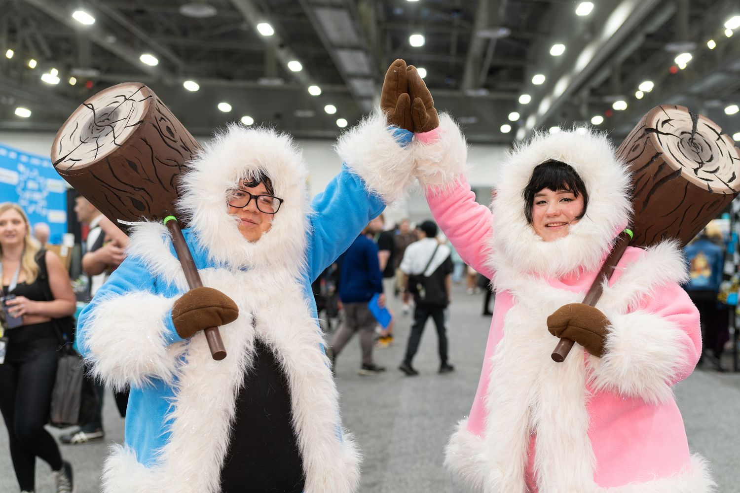 Group of furry cosplayers in white and pink costumes posing at convention.