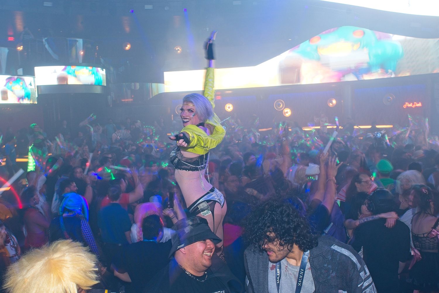 Crowded nightclub scene with colorful lighting and a packed dance floor.