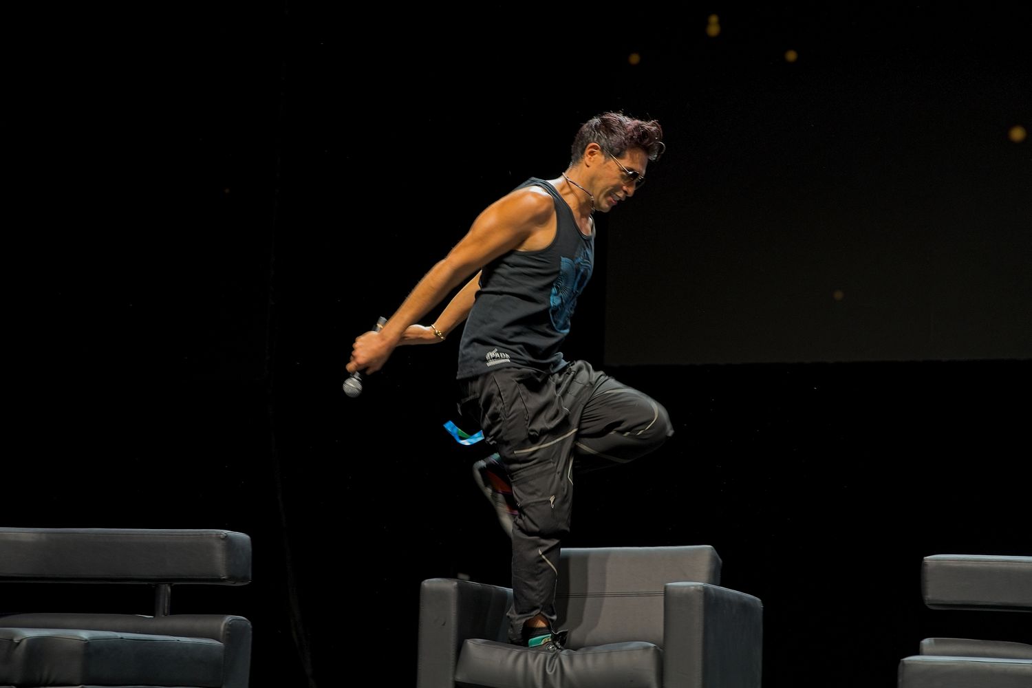 Performer jumping energetically on a dark stage during a live show.