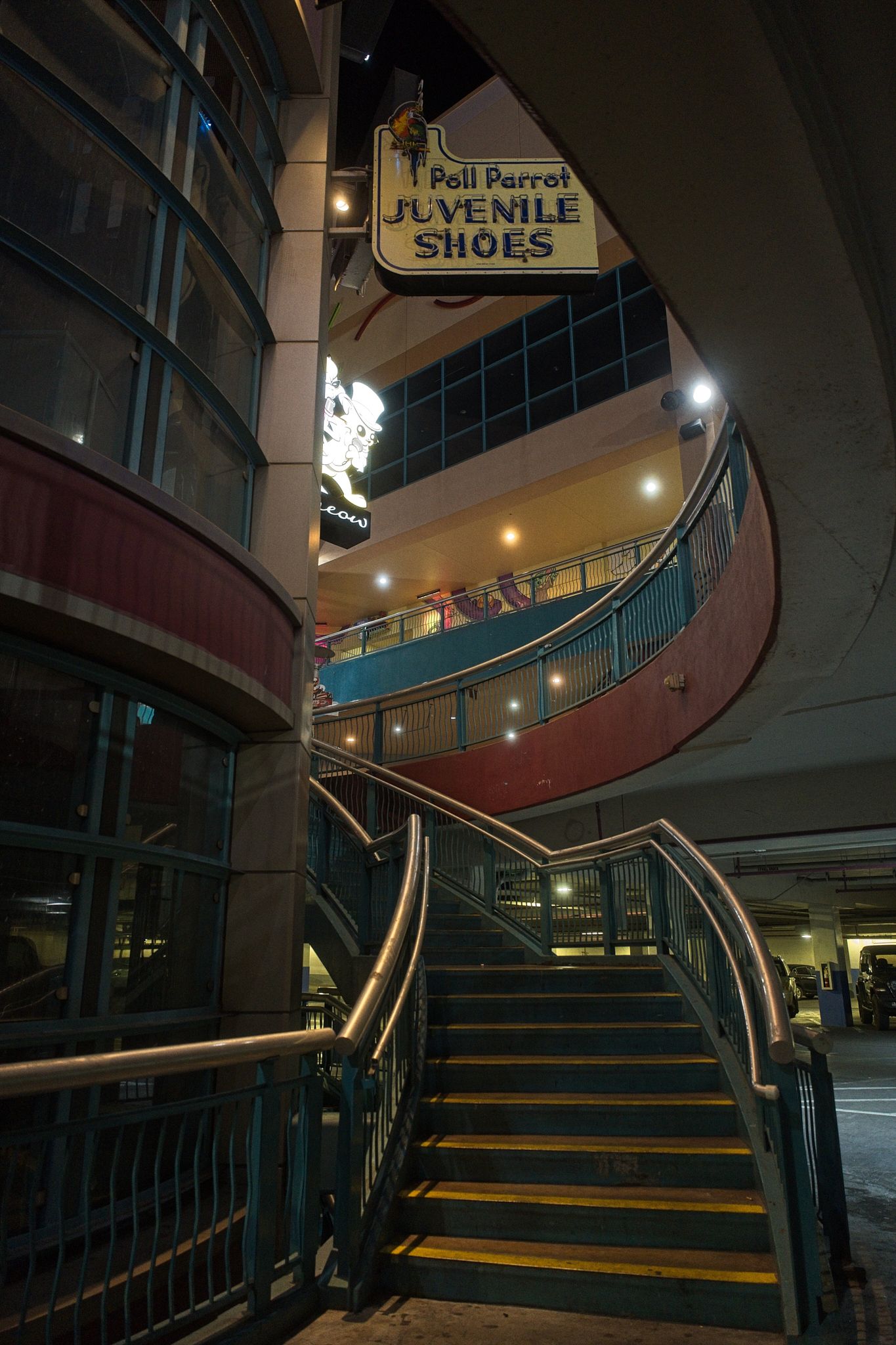 Dimly lit staircase with yellow safety strips in a modern shopping center or transit station.